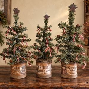 Three handmade primitive Christmas trees in different holiday containers